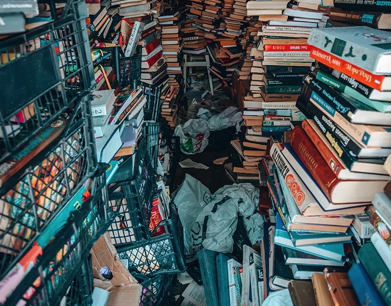 Narrow room with stacked books and storage crates during Hazel Park cleanup planning